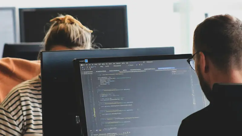 Entwickler arbeiten an Bildschirmen mit Programmcode